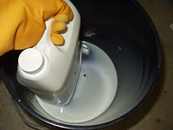 Leaky pesticide container being placed in 3-gallon bucket